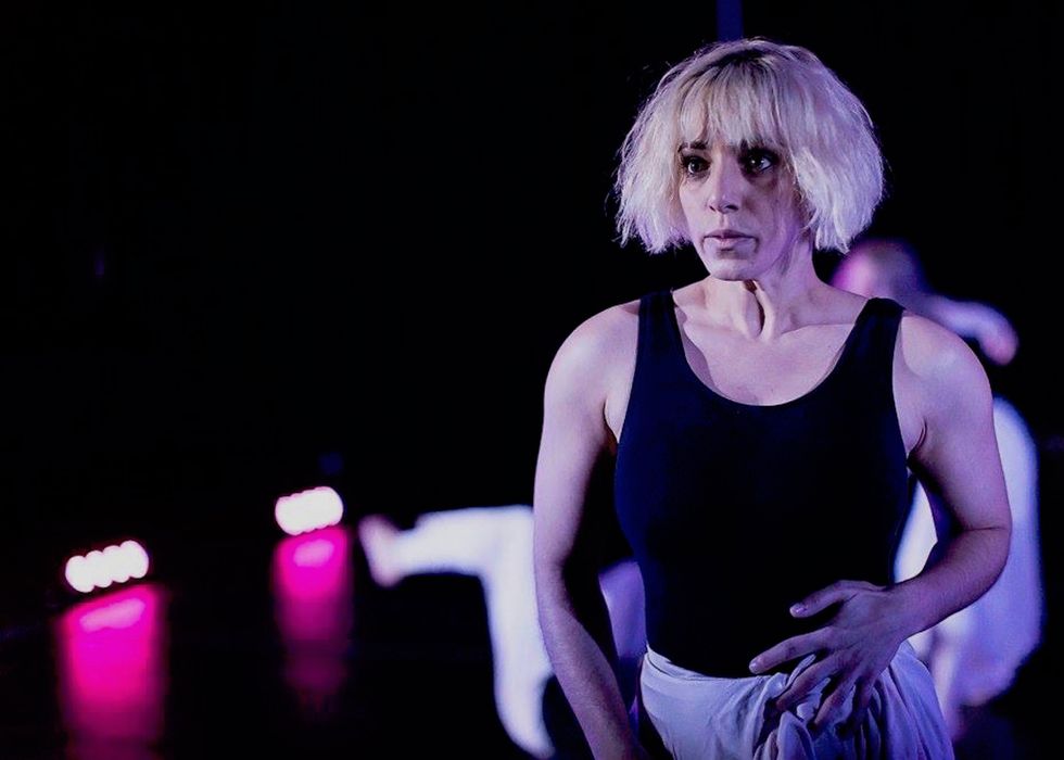 Danielle Georgiou stares intently at the audience from beneath the fringe of short blonde hair, one hand trailing up her stomach.