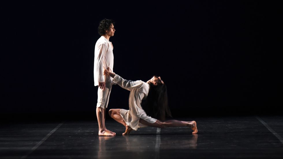 Herman Cornejo stares impassively offstage as Alessandra Ferri lunges deeply at his feet, her hands on his hips and her head arched back.