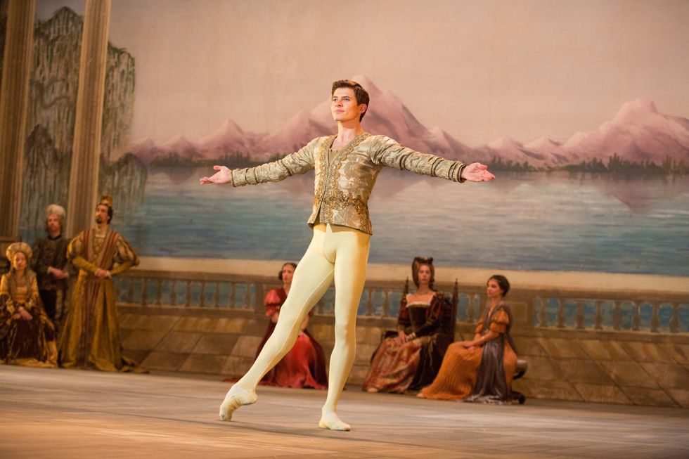 In The White Crow, Rudolf Nureyev, costumed in a gold costume and tights, prepares to turn during a performance.