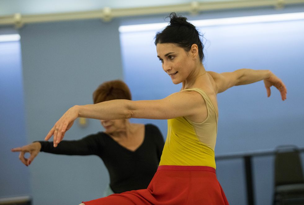 Lane tilts off balance as she extends her upstage leg forward at ninety degrees. Her opposite arm stretches forward as her torso twists away from the lean.