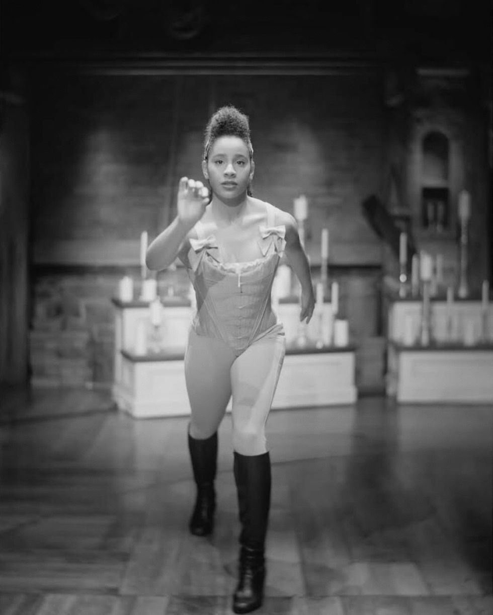 A black-and-white photo of Moore, in costume for Hamilton. She is lunging toward the camera.