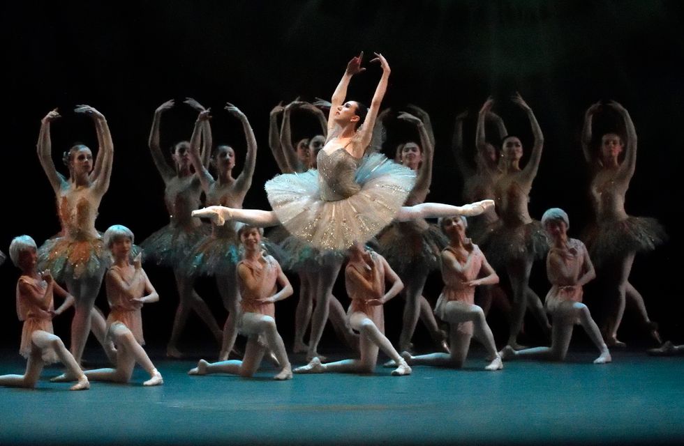 Boylston mid-leap in a classical ballet, with the corps de ballet posed behind her.