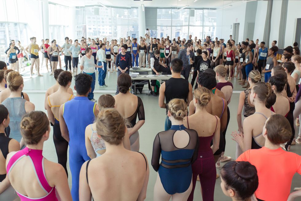 A crowd of auditioning dancers gather in a studio.