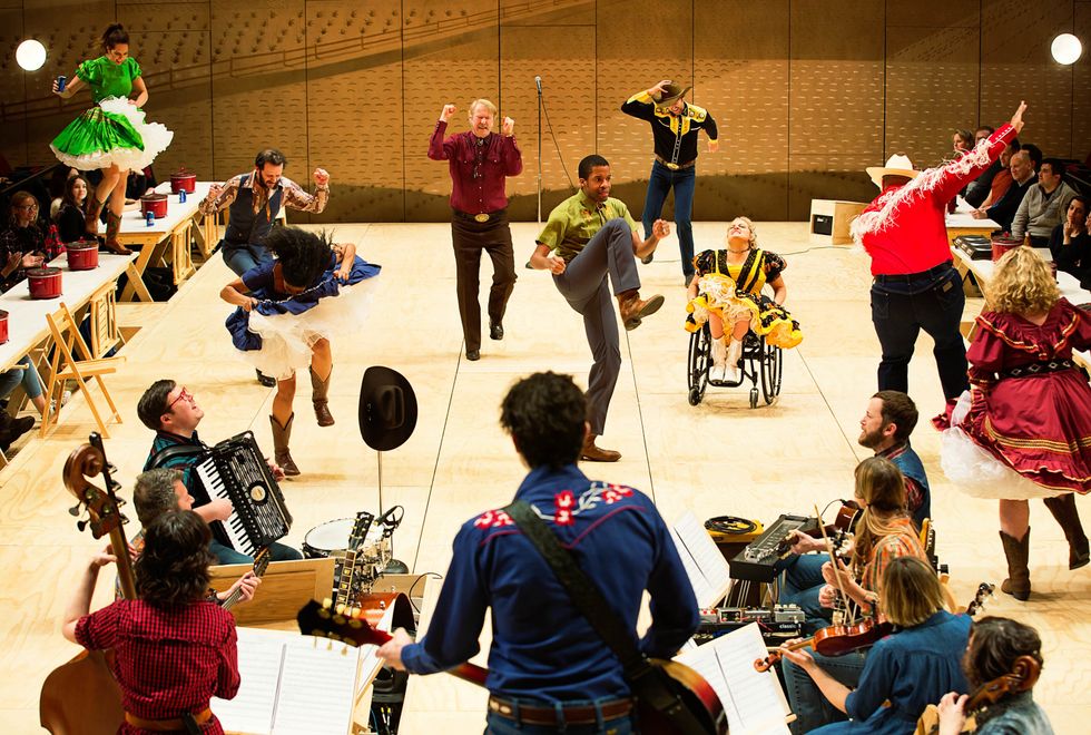 The cast of Oklahoma! in a dance scene, onstage with the show's band.