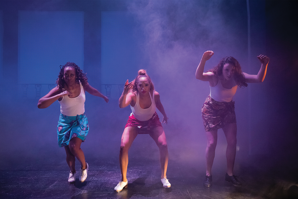 Three women tap on a smoky stage