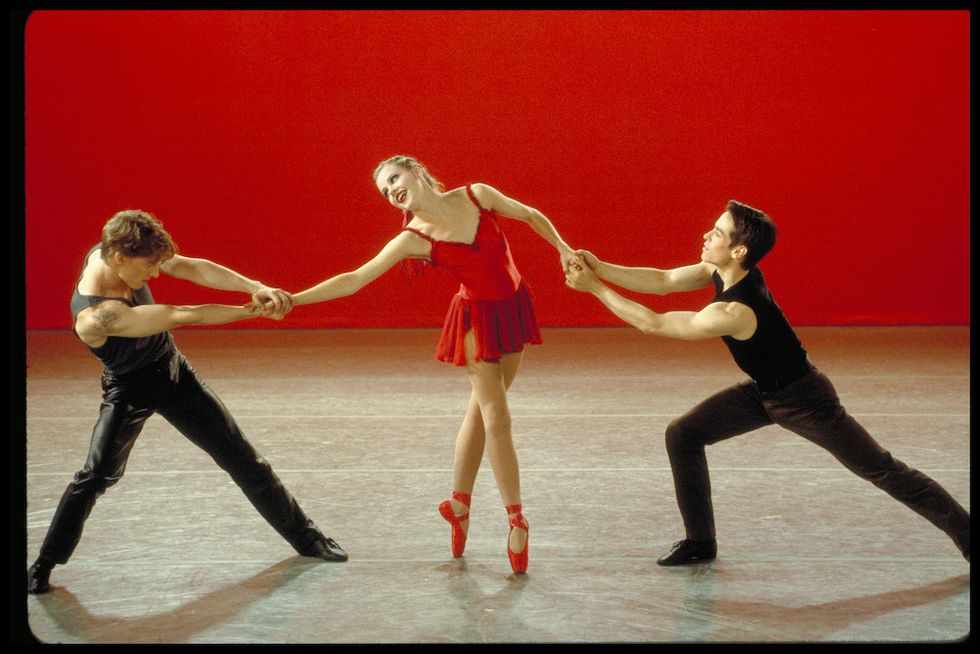 (From left) Steifel, Schull, and Radetsky dancing in "Cooper's ballet." Stiefel and Radetsky pull on Schull's arms as she stands on pointe in fourth position. Schull wears a red dress and red pointe shoes, and Radetsky and Steifel both wear black pants and tank tops.