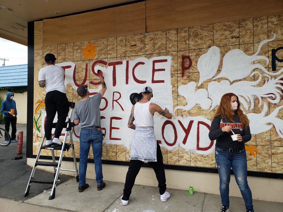 4 people in masks paint the mural on the side of Ananya Dance Theatre that says "Justice for George Floyd."