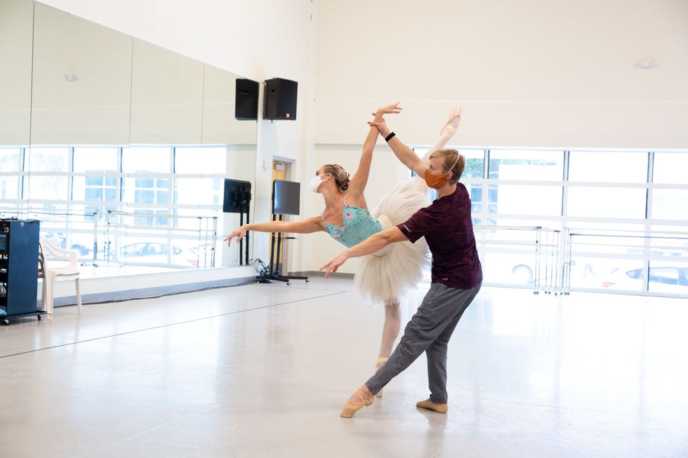 Fischer and her partner rehearse an arabesque in a studio, both wearing masks