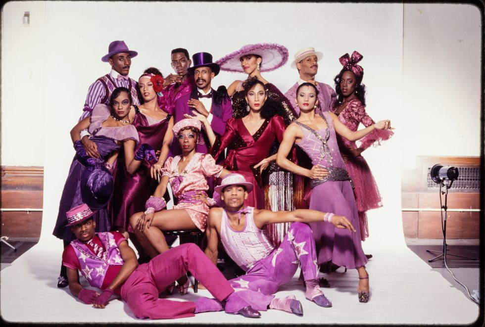 A group of dancers posing in purple and pink flashy, jazzy costumes