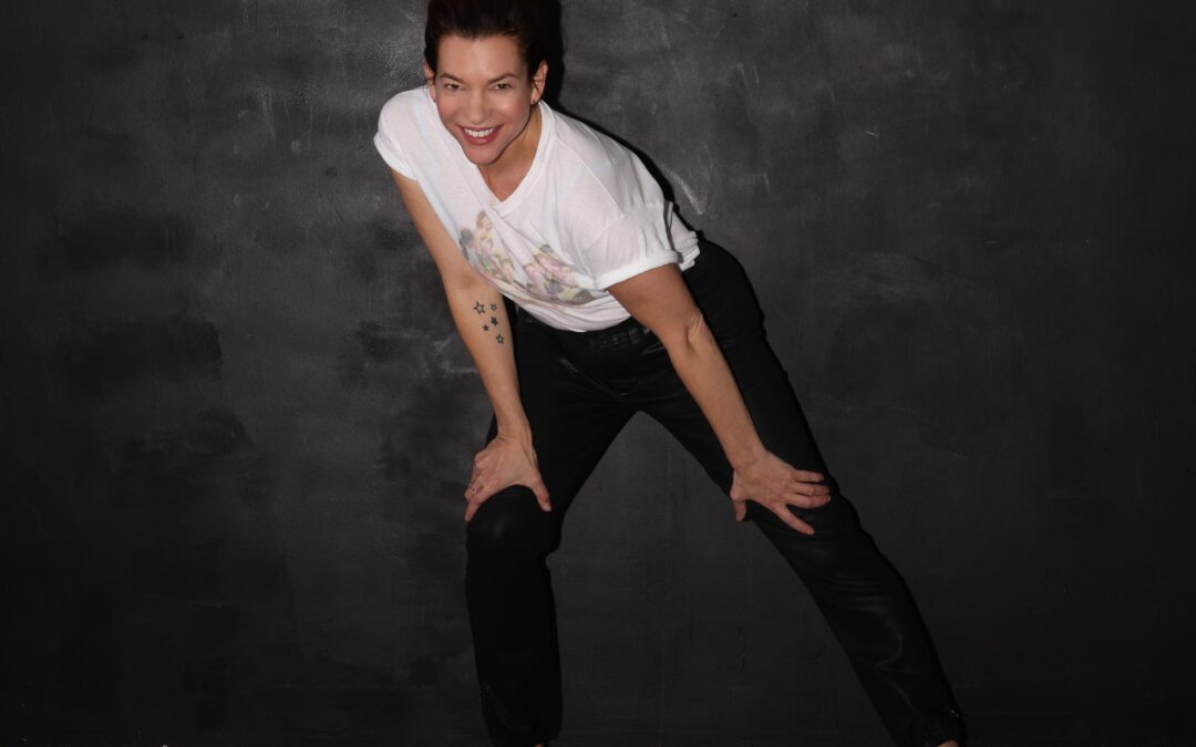 a woman wearing a white tshirt and black pants lunging side and smiling at the camera