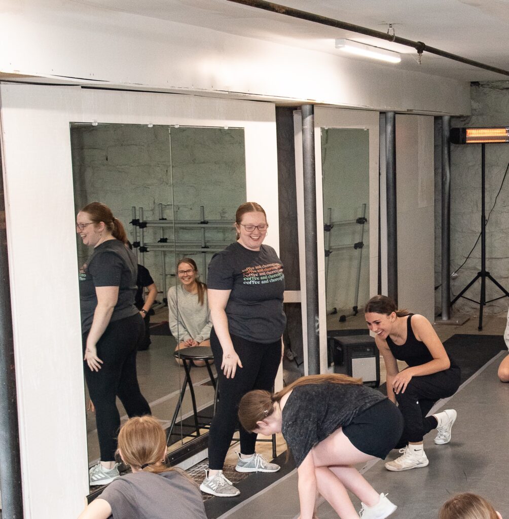 a female instructor standing while her students kneel on the floor 