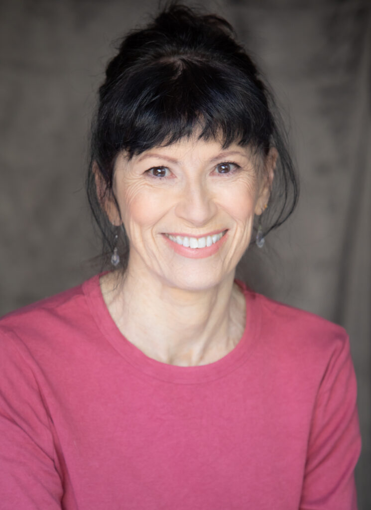 a woman wearing a pink shirt with dark hair smiling at the camera 