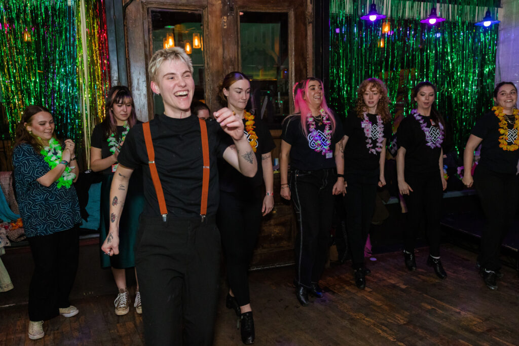 a group of dancers wearing black and leis on the dance floor