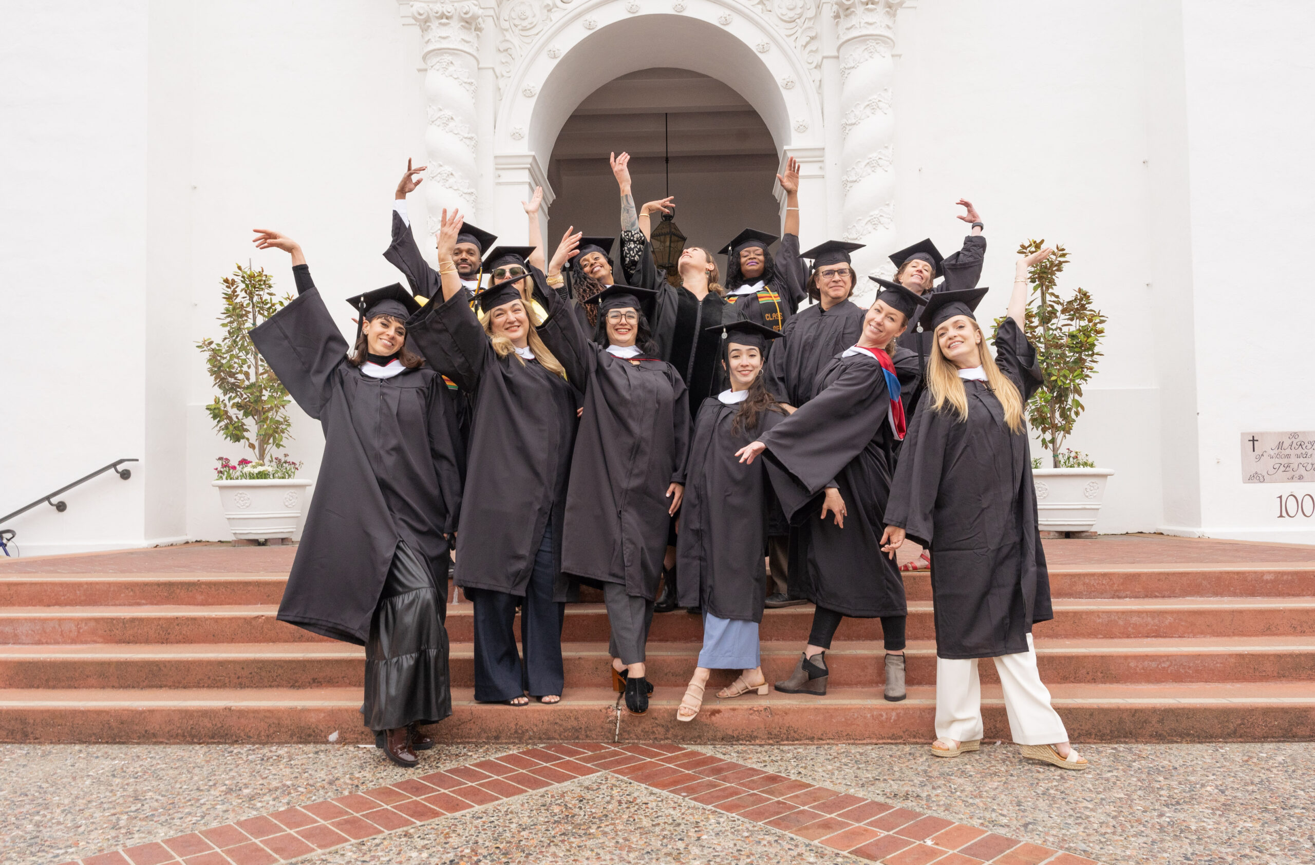 a group of dancers posing on steps wearing graduation caps and gowns