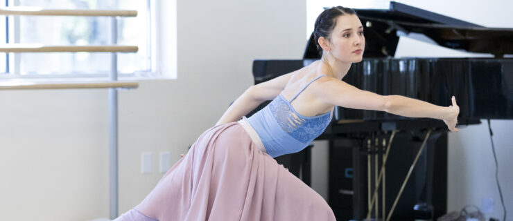 a female dancer lunging front in the studio with her opposite arm and leg extended out