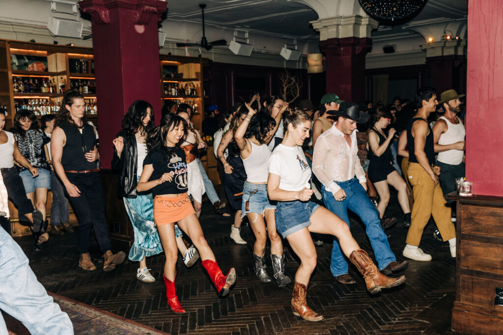 a large group of line dancers on the floor