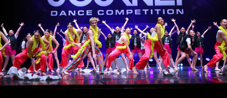 a large group of dancers on stage wearing bright colors and dancing big