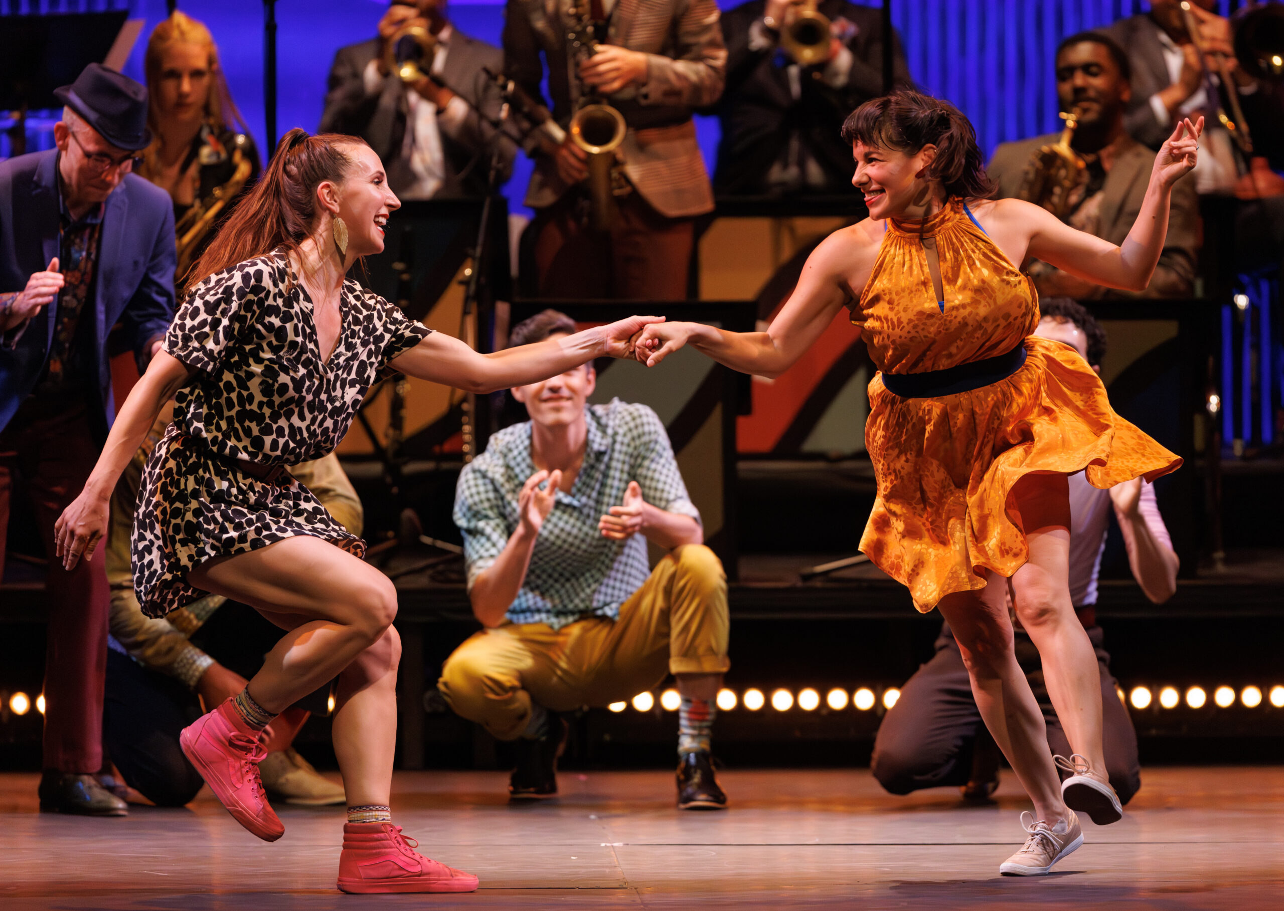 two female dancers swing dancing in the center with an audience watching on