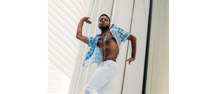 a male dancer wearing white jeans and a blue button down dancing on a bench with white columns