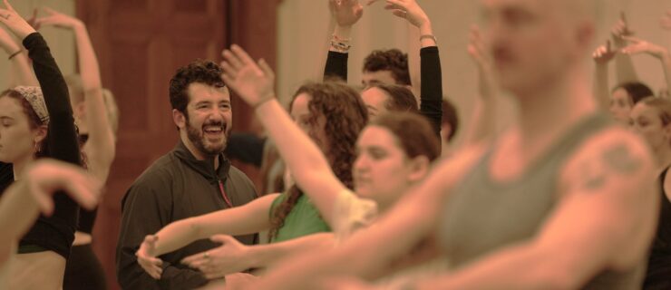 a male instructor smiling while watching a class full of students