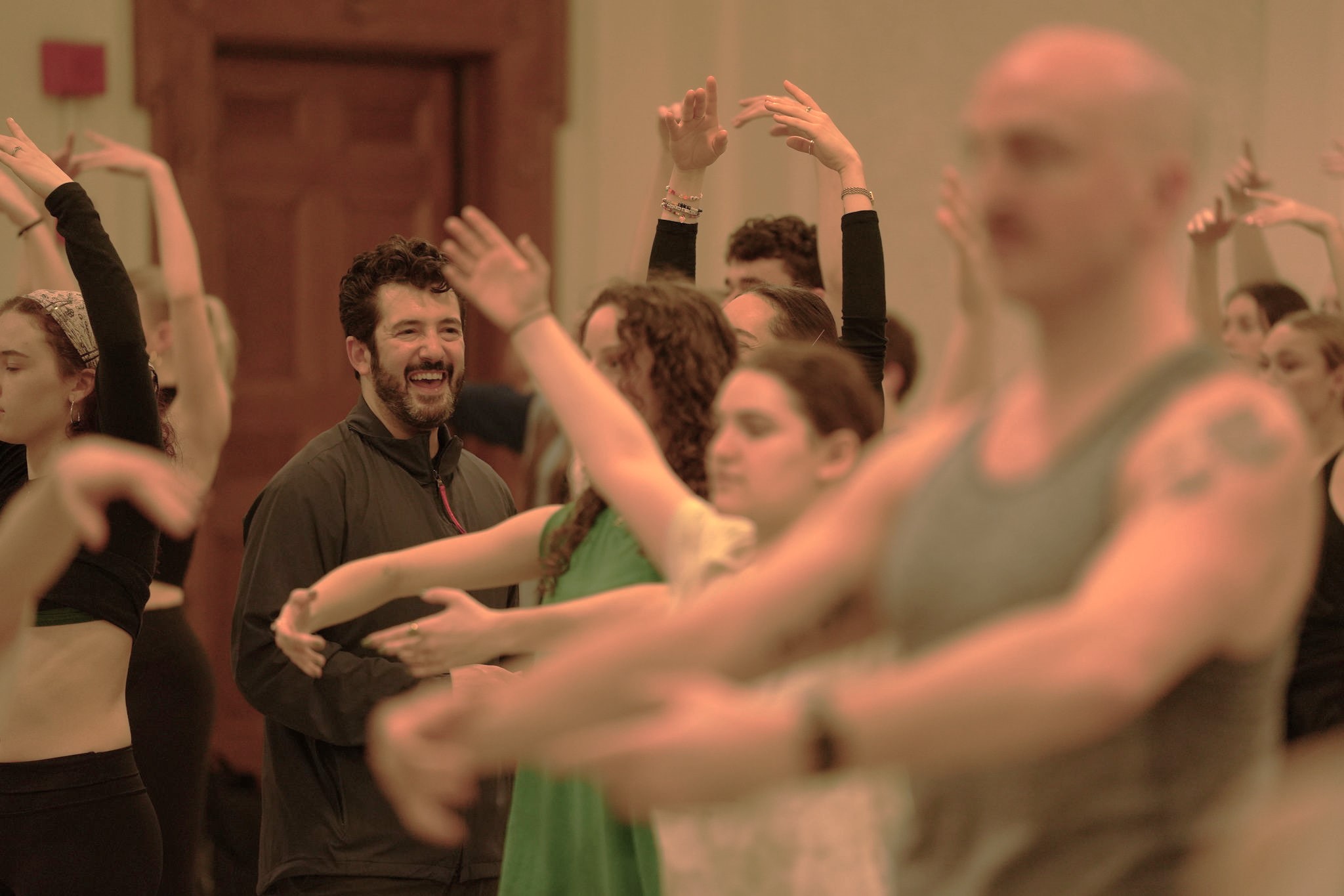 a male instructor smiling while watching a class full of students