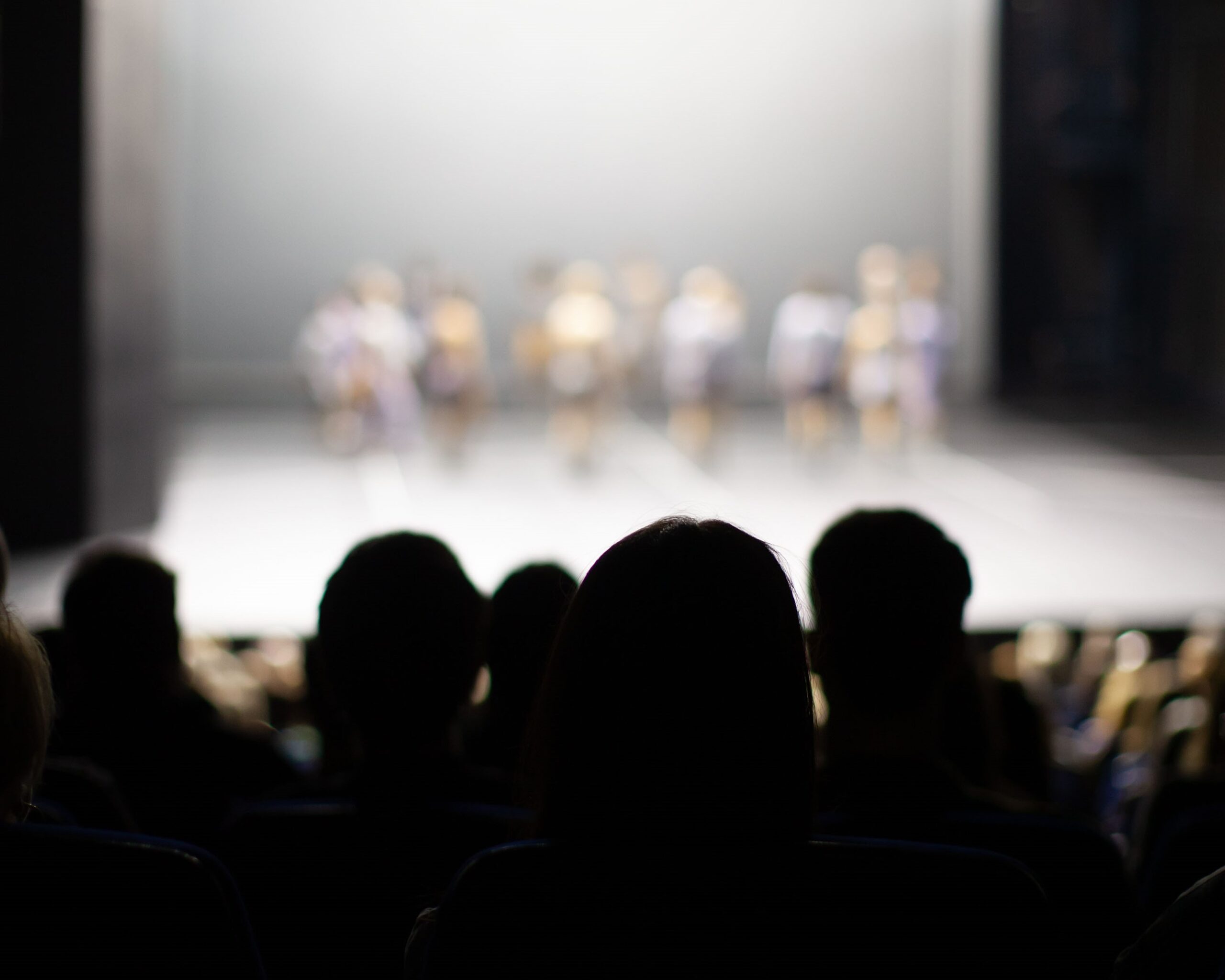 a group of people huddled together watching a dance performance on stage