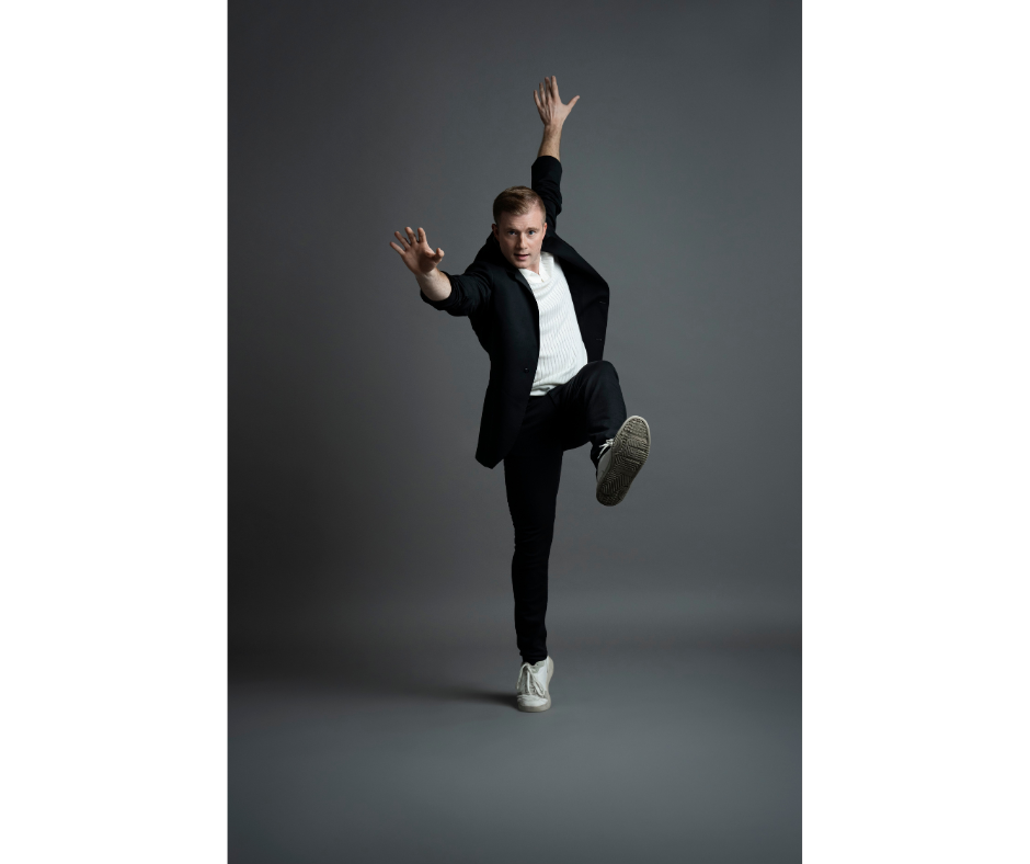 a male dancer wearing street clothes and sneaker posing in front of a grey backdrop