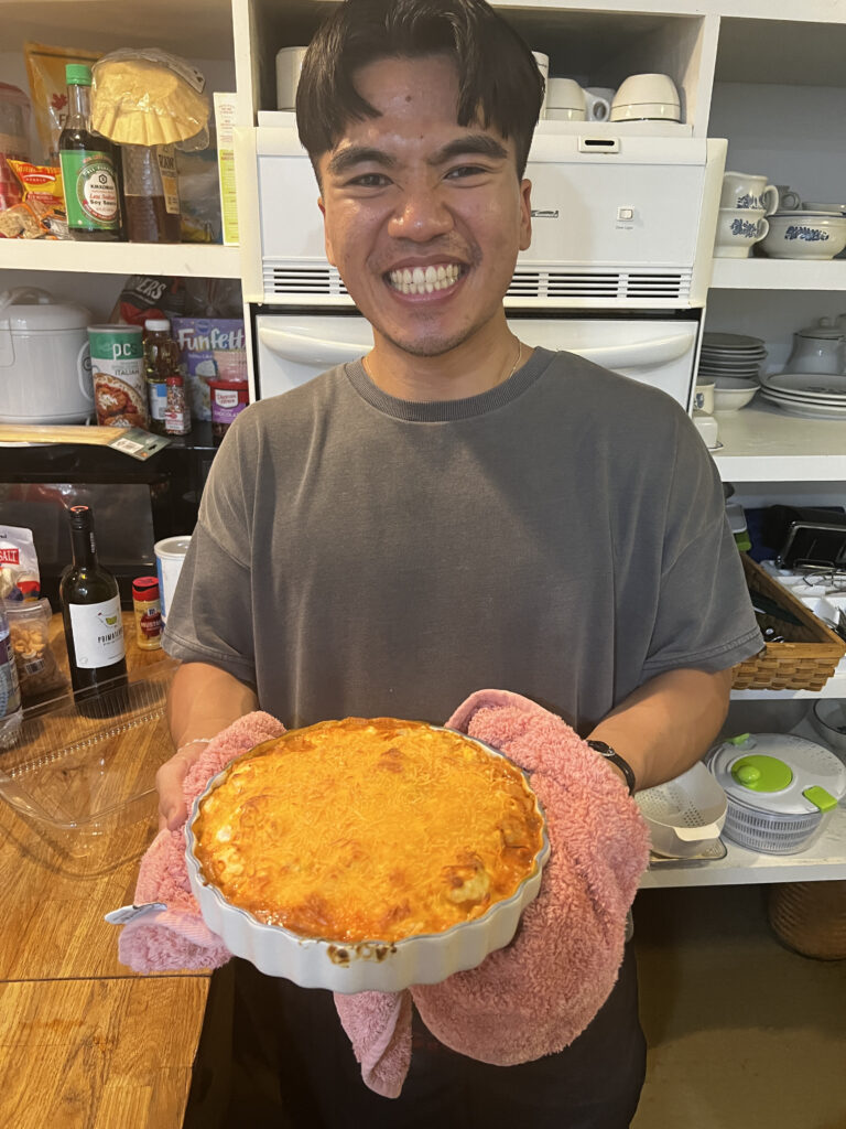 Austin Kelly holding a round dish topped with melted cheese 