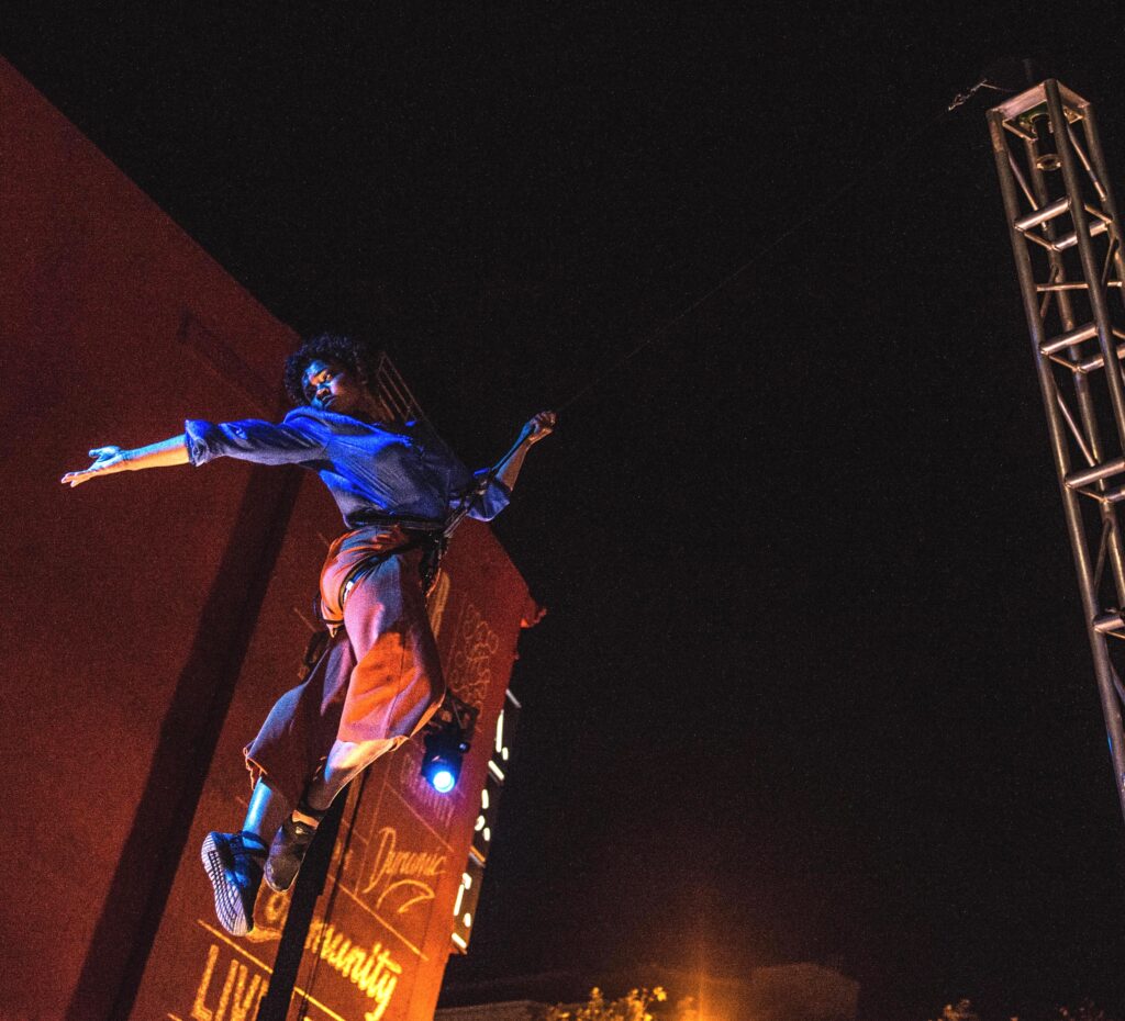 A female performer suspended in the air during an outdoor performance 