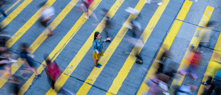 Young woman standing out, stationary in motion blurred crowd