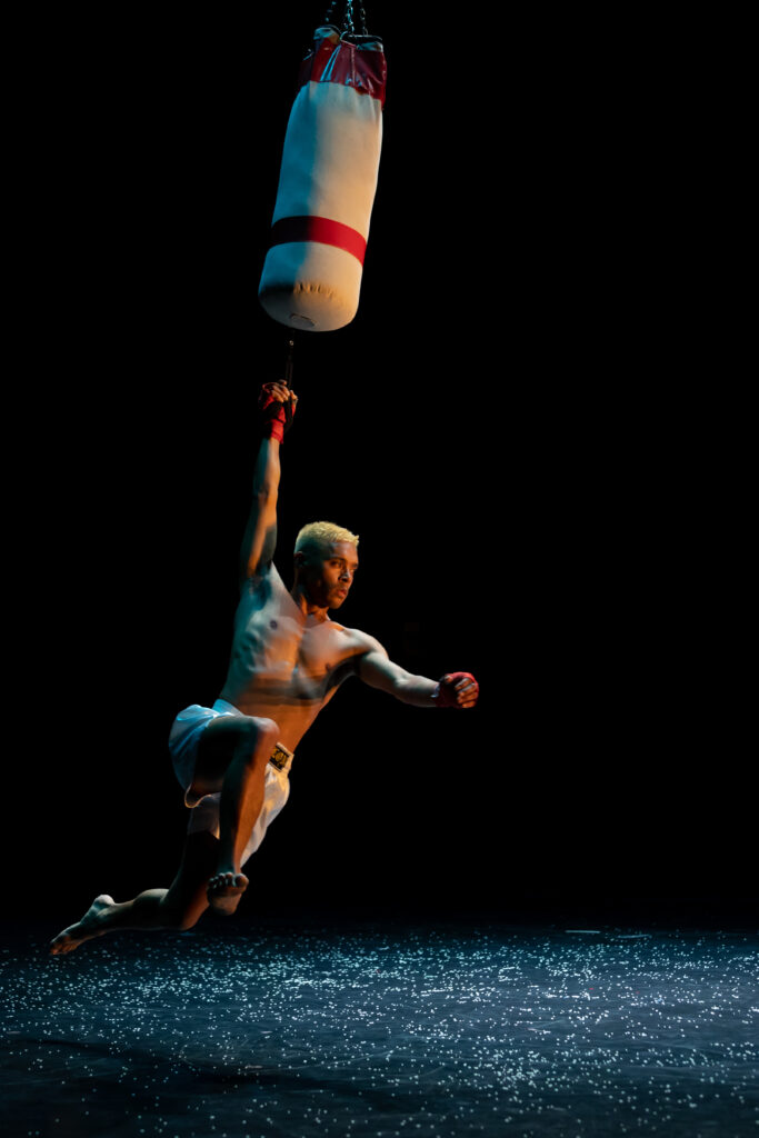 Jay Carlon hanging from a suspended bag on stage 