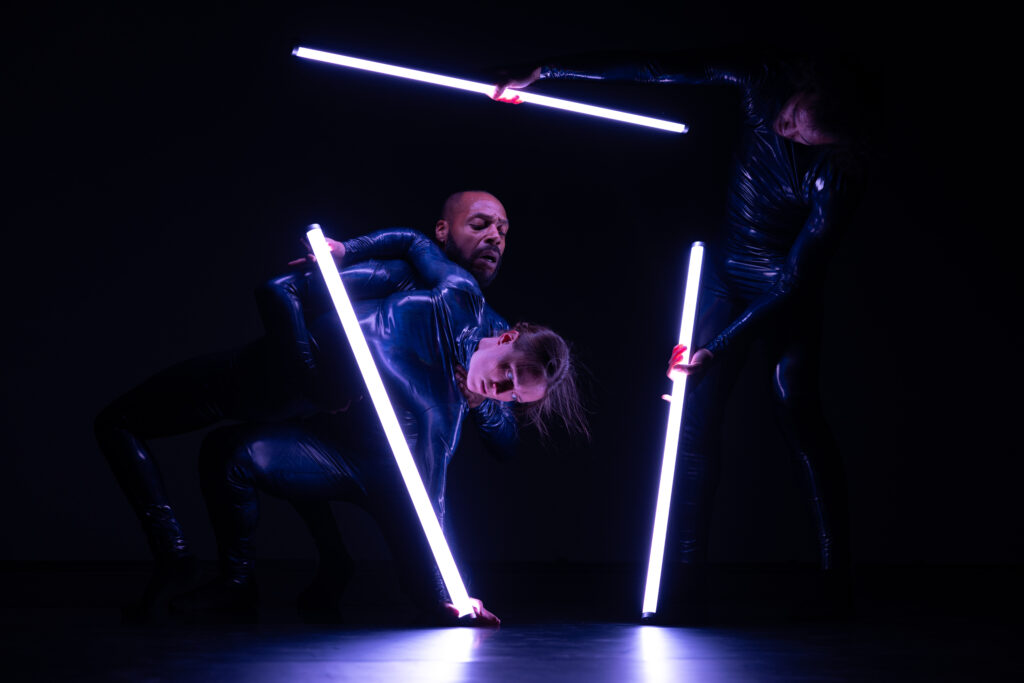 New Dialect artists performing in a dark space with beams of light 