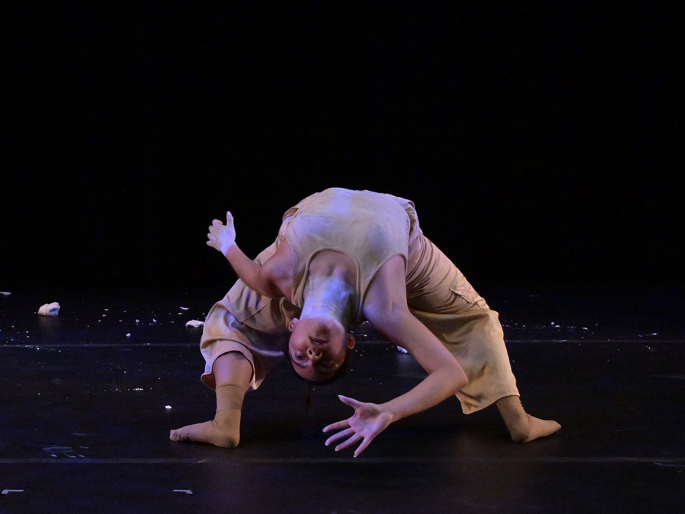 Nicole Pedraza hinging backwards on stage wearing neutral-colored clothing 