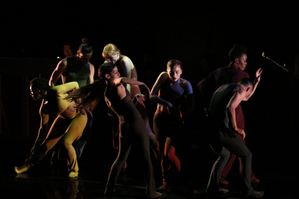 Owen/Cox Dance Group artists moving around a dimly lit stage 