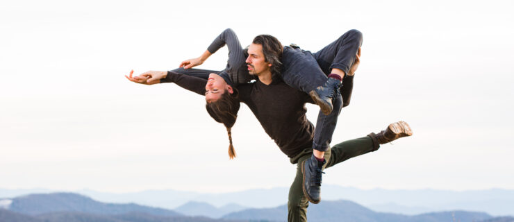 Gavin Stewart holding Vanessa Owen on his shoulders as they dance outdoors against a scenic background