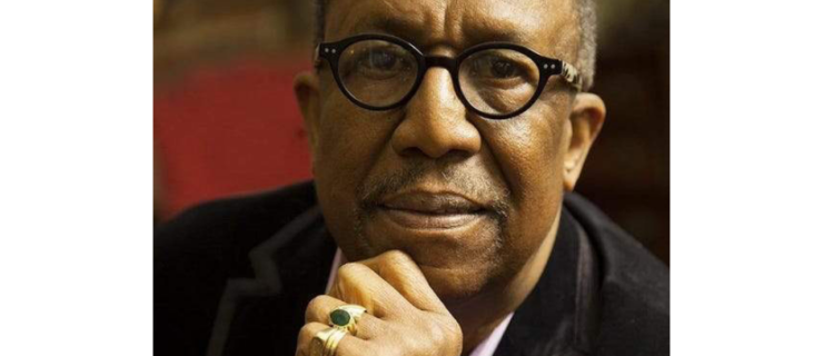 George Faison's headshot. He is wearing glasses and a suit while looking directly into the camera