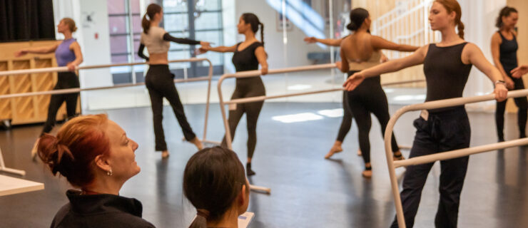 Jennifer Backhaus sitting at the front of the studio watching students perform exercises at the barre