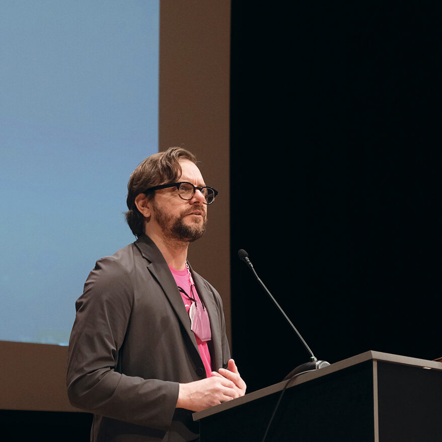 Sydney Skybetter standing at a podium on stage.