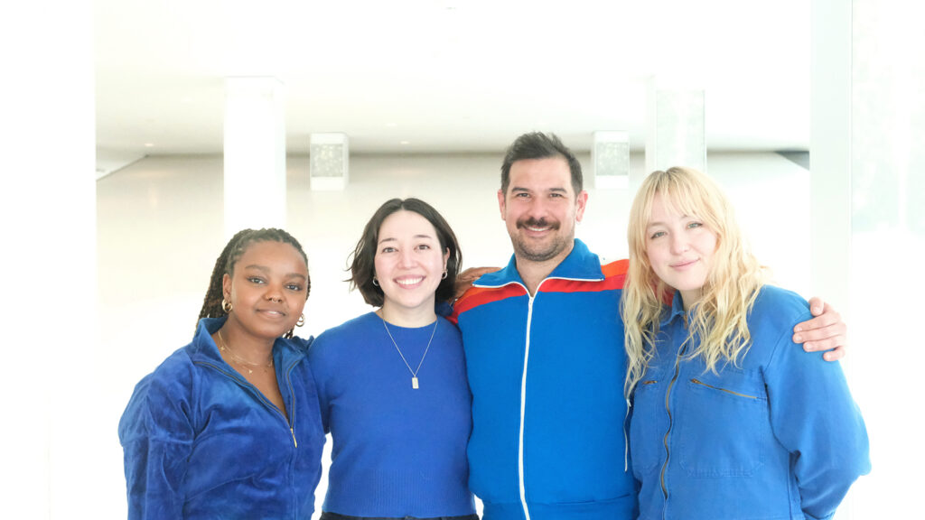 Four residents stand together, smiling for a photo. They all wear blue tops.