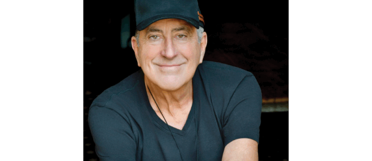 Kenny Ortega's headshot. He wears a t-shirt and baseball hat.
