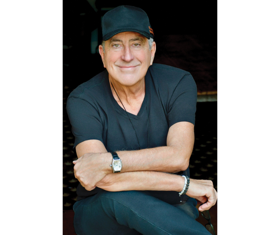 Kenny Ortega's headshot. He wears a t-shirt and baseball hat.