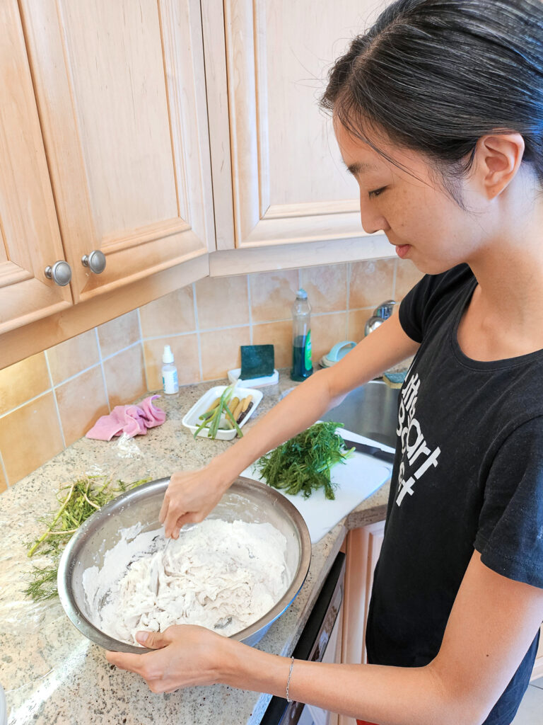 Agnes Su in the kitchen mixing a large bowl full of flour and other dumpling ingredients. 