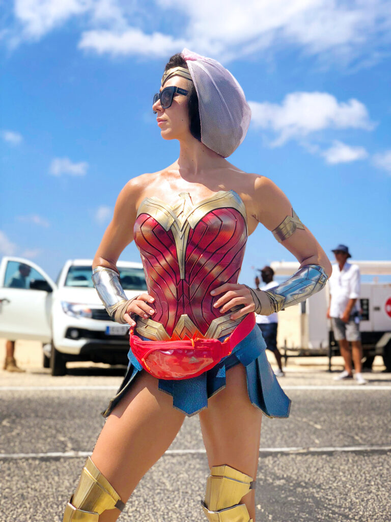 Christiaan Bettridge stands in a parking lot with her hands on her hips. She wears a Wonder Woman costume.