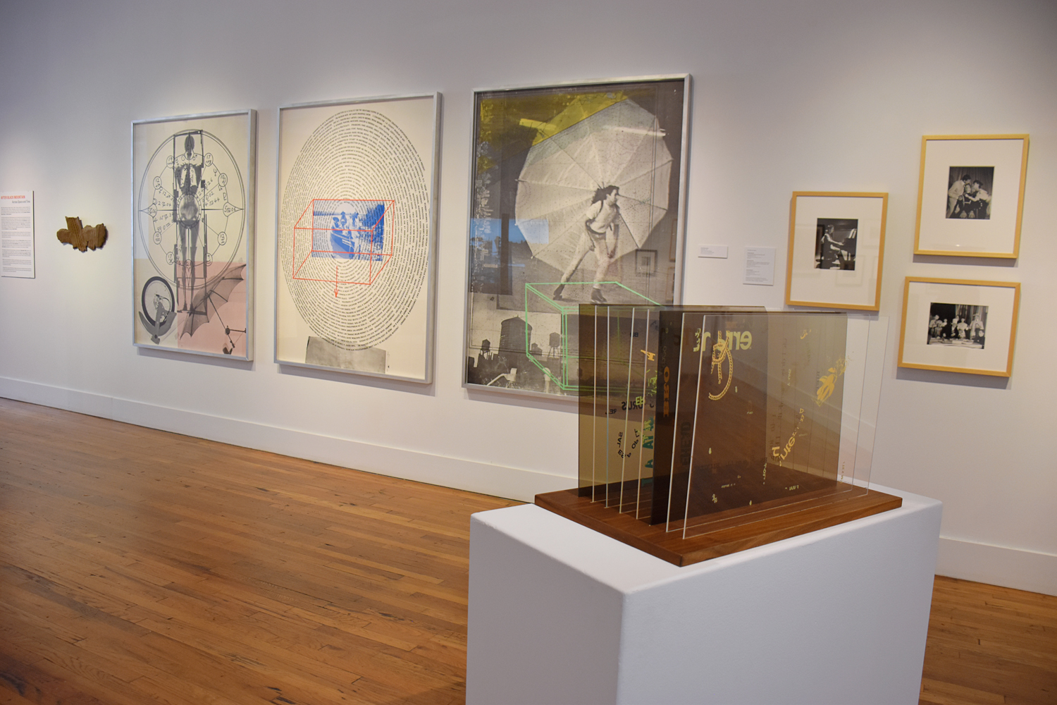 A gallery view of part of the "Points in Space" exhibition. Large and small artworks and performance images are framed on the white walls; a semi-transparent object is displayed on a plinth.