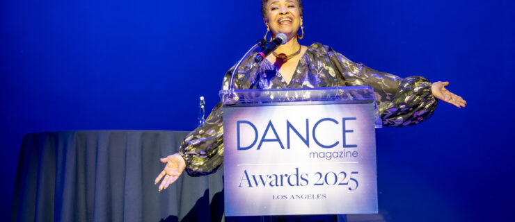 Allen, wearing a shimmering gold-and-black top, gestures emphatically as she stands at a podium labeled "2025 Dance Magazine Awards"