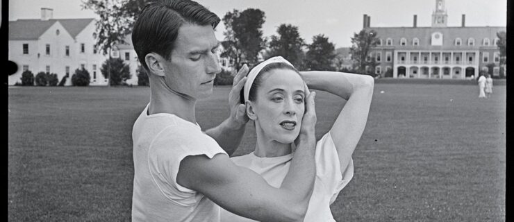 Martha Graham and Erick Hawkins stand on the lawn at Bennington's campus. Hawkins embraces Graham's head as she she poses with an arm around him.