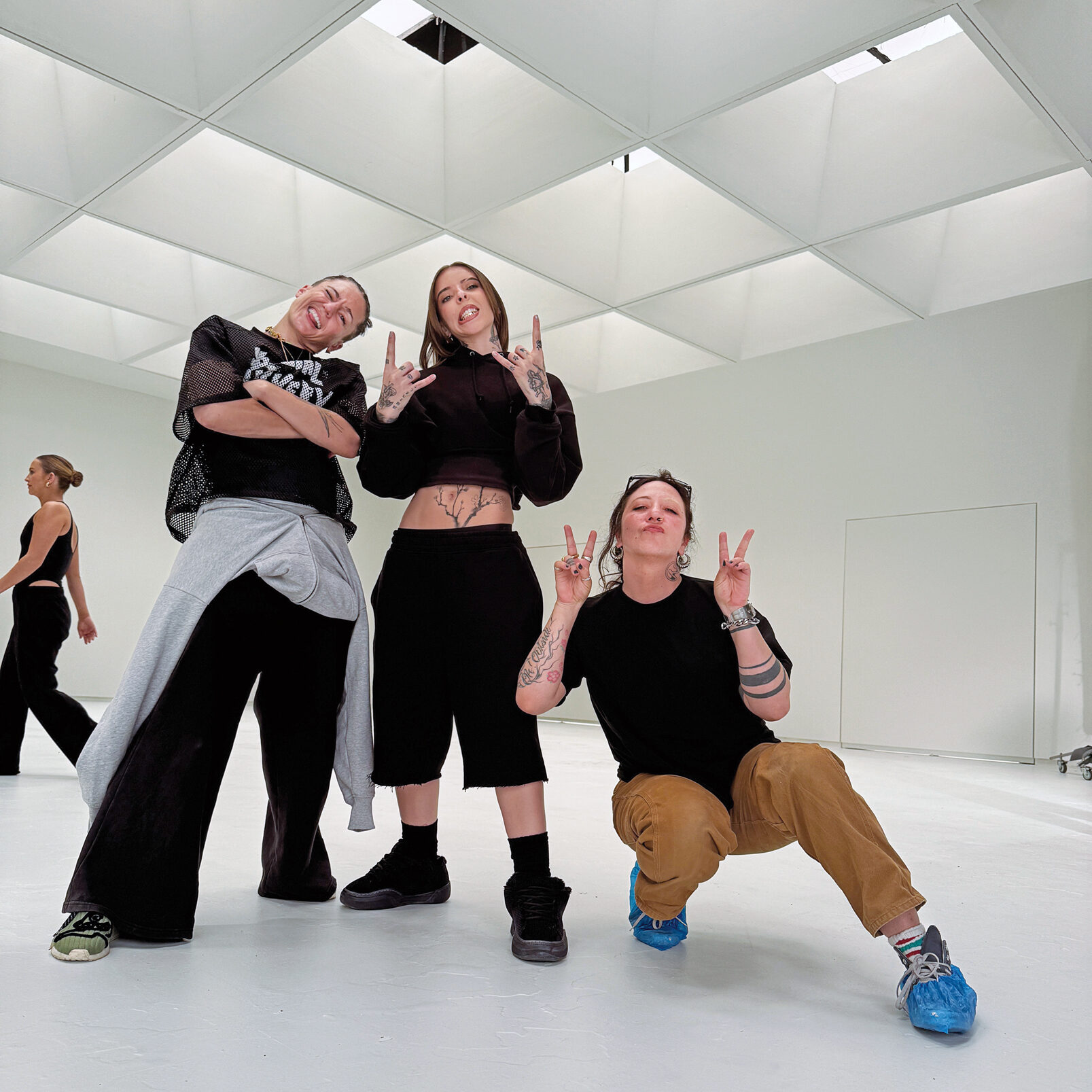Randi “Rascal” Freitas and Young Miko pose for a photo on set with choreographer Zoï Tatopoulos. The performers wear black hip hop style outfits. 