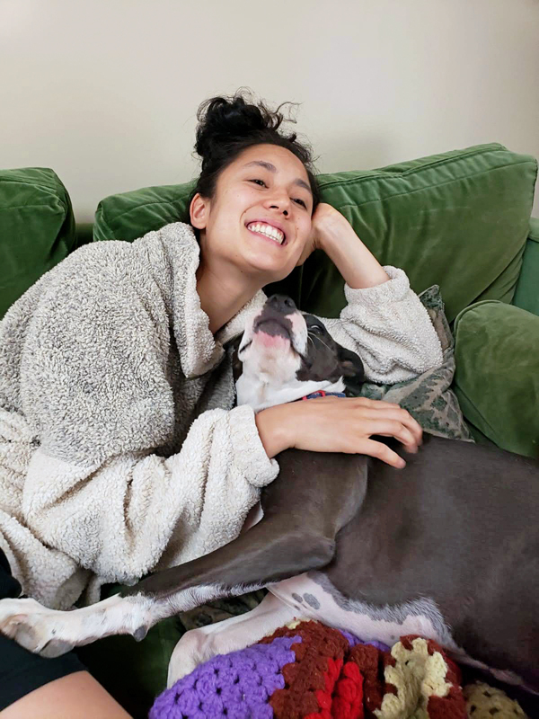 Leah Terada petting a dog on a green couch.