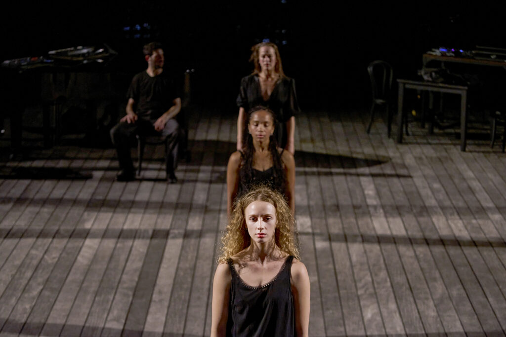 Johnson and other performers make a vertical line on stage. They stare forward with their arms by their sides.